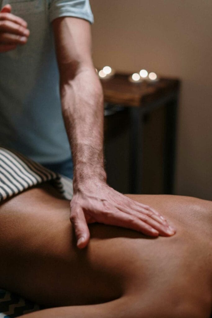 fisioterapia en Vélez Málaga | Persona recibiendo un masaje en la espalda por un profesional en un entorno relajante con velas.